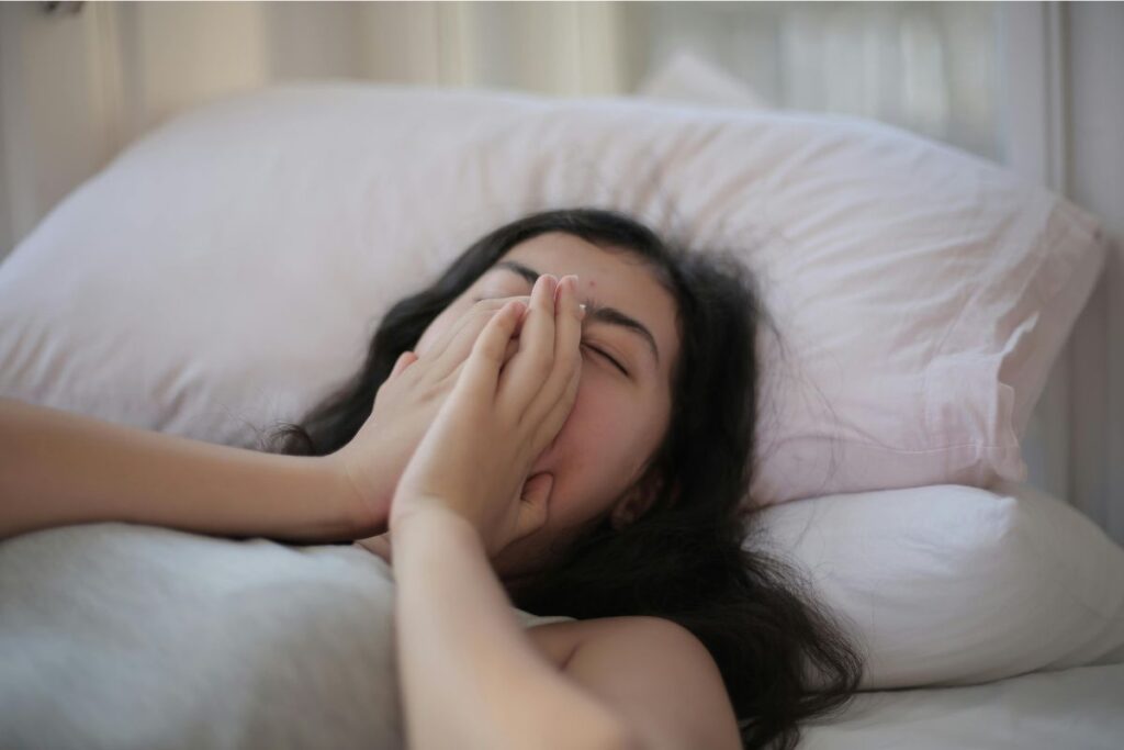 Woman7 waking up in bed feeling exhausted and tired after poor sleep during the night.