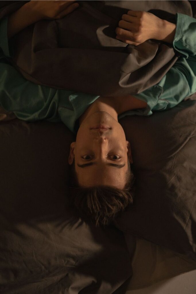 Why do I wake up feeling restless 
Young man lies awake in bed under dim lighting