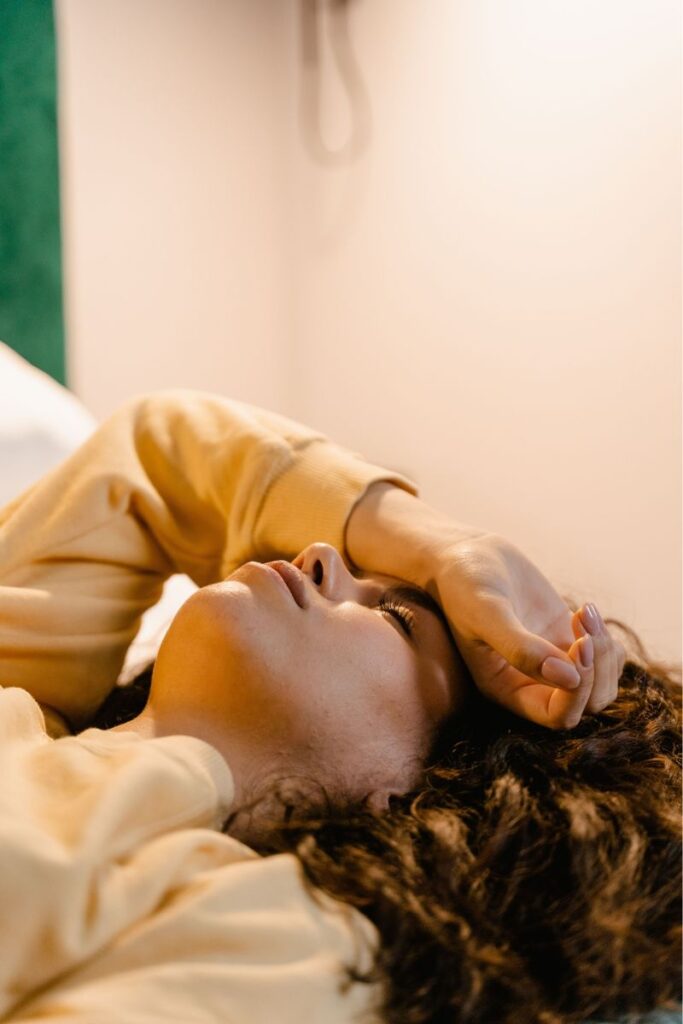 woman waking up feeling dizzy in bed in the morning